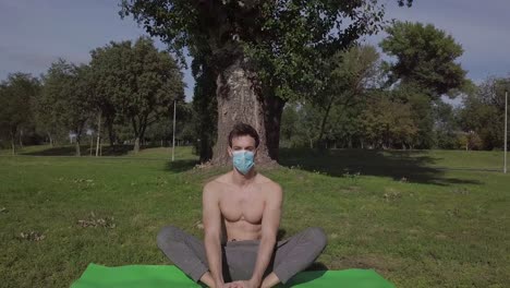 Junge-Brünette-Frau-Mit-Maske-Sitzt-Und-Macht-Yoga-Übungen,-Während-Sie-Vor-Dem-Computer-Schaut