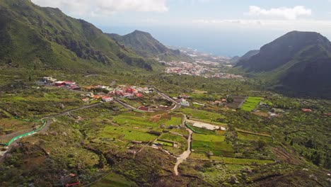 Beautiful-Drone-perspective-shot-of-Tenerife-Valley-township-surrounded-by-lush-green-mountains