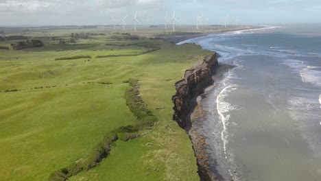 Beautiful-aerial-view-over-scenic-coastal-landscape-to-wind-farm-in-New-Zealand