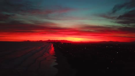 Descending-aerial-4k-drone-shot-of-burning-red-sky-in-Brazil,-unreal-color-sky-and-ocean