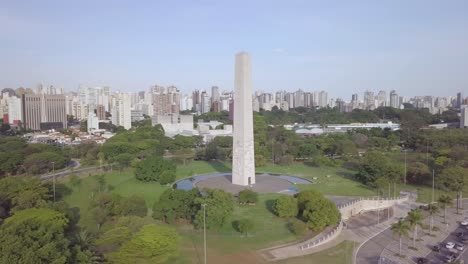 Orbiting-aerial-shot-of-monument-and-skyline-of-Sao-Paolo-in-tourist-street-near-Ibirapuera-Park,-Brazil