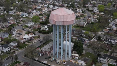 An-aerial-view-of-a-water-tower-in-Elmont,-New-York-under-a-tarp-on-a-cloudy-day