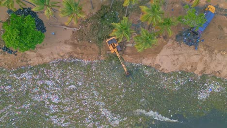 Aerial-top-down-of-excavator-on-beach-cleaning-ocean-full-of-plastic---environmental-pollution