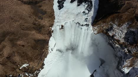 Impresionante-Cascada-Congelada-De-Skogafoss-Que-Fluye-Con-Fuerza-Poderosa,-Aérea