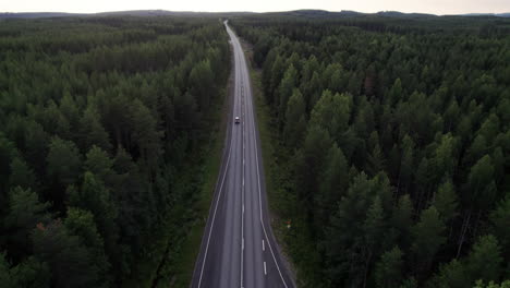 Aerial-View-of-Car-Passing-on-a-Lonely-Forest-Road-in-Northern-Finland,-Lapland