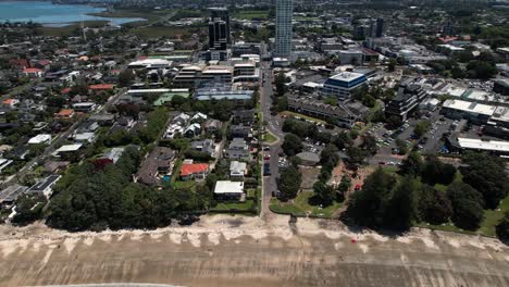Aerial-reveal-high-buildings-over-Takapuna-Beach-in-Auckland,-New-Zealand