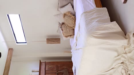 Vertikal-–-Aus-Der-Perspektive-Einer-Person,-Die-Eine-Villa-Mit-Böhmischem-Schlafzimmer-Durch-Eine-Tür-Betritt,-Die-Ein-Gemachtes-Bett-Und-Exotisches-Balinesisches-Holzdekor-Freigibt