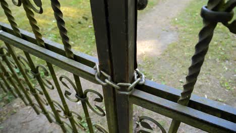 Chain-on-a-metal-fence-with-a-garden-behind-it