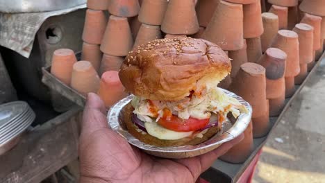 Lokaler-Burger-Mit-Tomaten-Und-Gurken-Mit-Kulhad-Oder-Bhand-Im-Hintergrund-In-Gaya,-Bihar