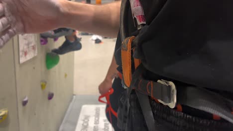 Man-secures-himself-with-a-harness-before-proceeding-to-climb-a-wall