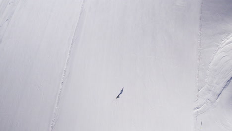 Top-down-drone-shot-of-lonely-skier-on-large-ski-slope-in-Austria