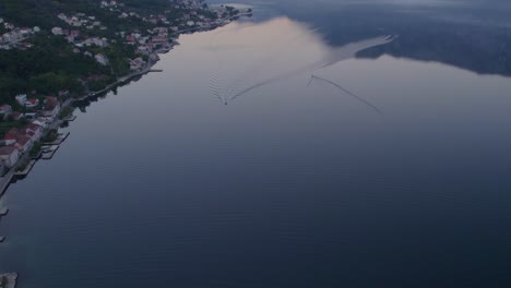 Tilt-up-shot-of-Kotor-bay-with-small-fishing-boats-during-sunrise,-aerial