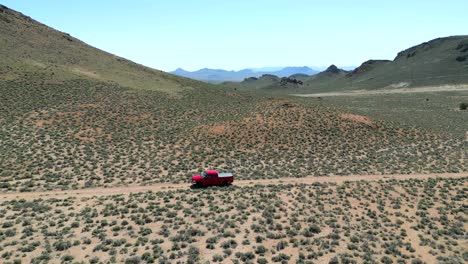 Luftaufnahme-Eines-Roten-Lastwagens,-Der-Im-Frühling-Abseits-Der-Straße-Durch-Die-Wüste-Von-Nevada-Fährt,-Mit-Leuchtendem-Grün-Und-Buntem-Sand