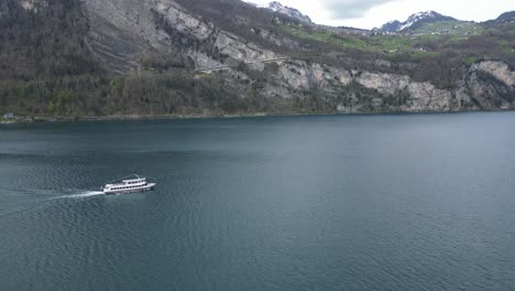 Beautiful-cruise-ship-forming-bow-wave-ripples-in-Walensee-lake,aerial