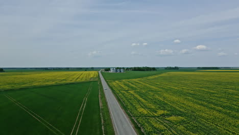 A-car-and-truck-driving-along-a-road-in-farmland-countryside---aerial