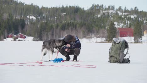 Backpacker-With-His-Dog-Fishing-In-The-Frozen-Lake