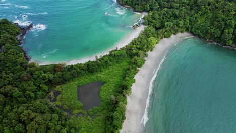 Sobrevuelo-De-Drones-Mar-Azul-Tropical-Que-Rodea-El-Promontorio-De-La-Playa-De-Manuel-Antonio-Con-árboles-Verdes,-4k-Antena-Costa-Rica