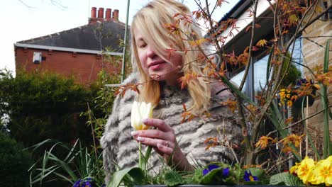 Attractive-woman-enjoying-enjoying-scent-of-flowers-in-garden-medium-zoom-in-shot-slow-motion-portrait