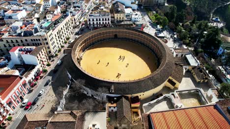 Aerial-descending-view-of-Ronda-Spain-cityscape,-park,-amphitheater
