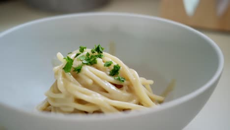 Close-up-sprinkle-herbs-over-beautifully-arranged-Italian-spaghetti-pasta-dish