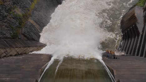 Top-down-handheld-shot-of-Hinze-Dam-overflow-under-heavy-rain-during-La-Niña,-Gold-Coast-Hinterland,-Queensland,-Australia