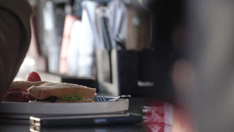 Slow-motion---Hand-of-person-with-sandwich-placed-on-white-plate-on-table
