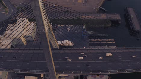 Drone-aerial-view-of-traffic-flowing-over-a-suspended-bridge-across-a-river