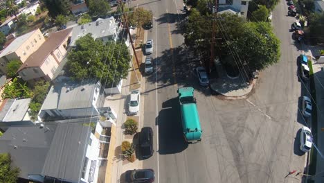 garbage-truck-picking-up-trash-on-city-streets---aerial