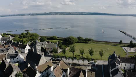 Aerial-view-starting-in-the-houses-of-Culross,-Scotland-and-ending-up-over-the-quaint-waters
