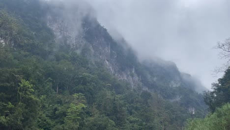 Panshot-of-misty-white-limestone-mountain-ridge-with-thick-evergreen-jungle-at-the-bottom