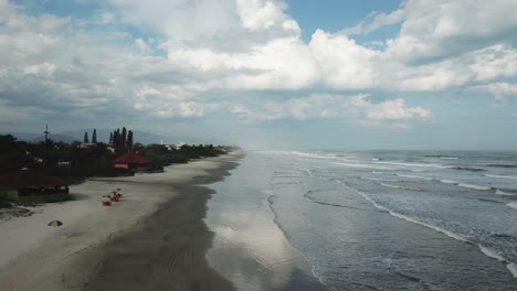 Wunderschöner-Drohnenflug-über-Strand-Und-Meer-Mit-Großen-Wellen-Und-Wolken,-Itanhaem-Brasilien