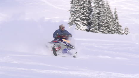 Male-snowmobiler-backcountry-powder-slow-motion-cinematic-mid-winter-fresh-snow-blue-skies-Colorado-at-Vail-Pass-early-morning