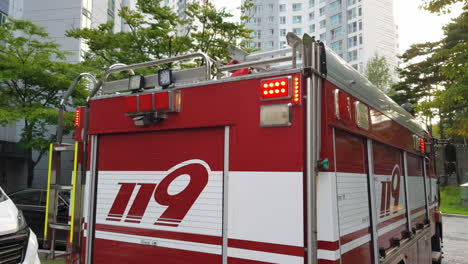 Rear-Of-119-Firetruck-In-South-Korea,-Equipped-With-Ladder-And-Flashing-Emergency-Lights