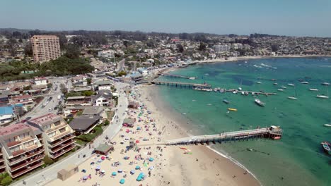Flyover-of-the-calm-and-relaxing-beach-of-Pejerrey-in-Algarrobo-on-a-sunny-day,-Chilean-coastline,-in-dolly-in-drone-shot