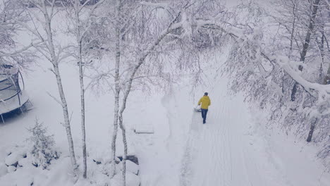 Aerial-bird's-eye-view-of-man-shoveling-heavy-snow,-winter-white-landscape