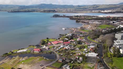 Aerial-scenic-view-of-fakefront-of-Lake-Rotorua-and-Ohinemutu-village-during-sunny-day,-New-Zealand