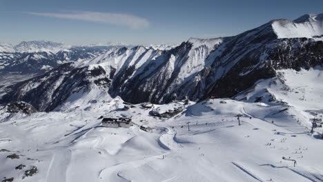 Toma-Cinematográfica-De-Drones-Del-Paisaje-De-Montaña-Blanca-Con-área-De-Esquí-Y-Remonte-En-Invierno-Austriaco