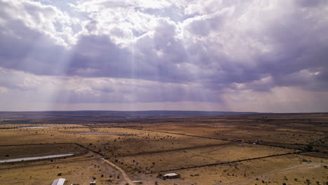 Stunning-hyperlapse-featuring-a-golden-plain-during-the-dry-season,-with-intense-clouds-in-the-sky-and-gaps-for-sun-rays-to-shine-through,-creating-a-spectacular-sunbeam-display