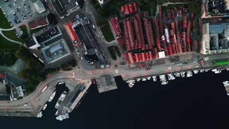 Top-down-tracking-shot-of-a-small-port-with-boats,-houses-and-some-factory-buildings-can-be-seen-from-above,-daytime,-no-people