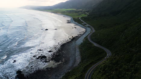 Cars-traveling-on-seaside-road-near-Ruatapu,-New-Zealand