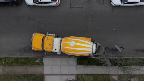 A-top-down-view-over-a-yellow-and-white-cement-truck-in-a-residential-neighborhood-on-a-cloudy-day