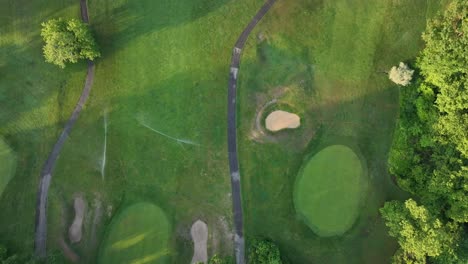 An-aerial-top-down-view-of-a-well-maintained-golf-course-in-Queens,-New-York-during-a-sunny-morning-while-the-sprinkler-system-is-turned-on