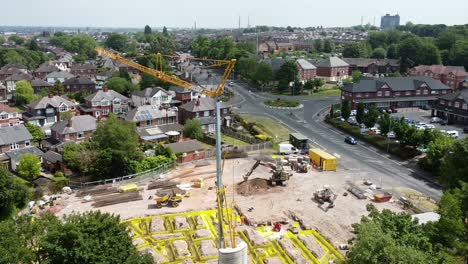Tall-crane-setting-building-foundation-in-British-town-neighbourhood-aerial-view-above-suburban-townhouse-skyline