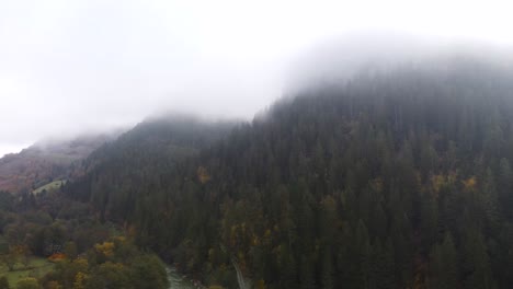 Stunning-mountain-cliffs-hidden-in-the-clouds,-early-autumn-morning,-orbit-drone-shot