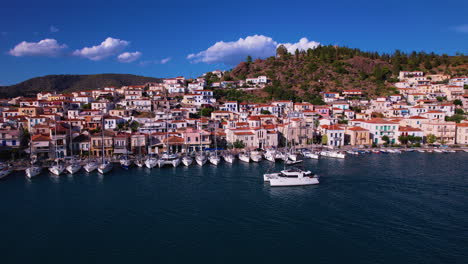 Catamaran-Yacht-cruising-past-a-boat-village-in-Greece