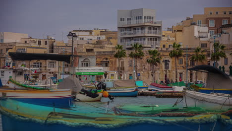 Colorful-small-boats-and-Maltese-township-behind,-time-lapse-view