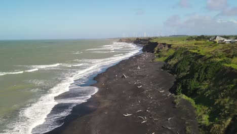 Drone-flyover-black-sand-beach,-coastal-scenic-on-North-Island,-New-Zealand