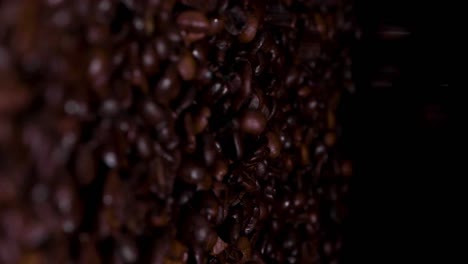 Slow-motion-vertical-shot-of-coffee-beans-falling-against-a-black-background