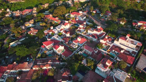 Drone-flyover-Touristic-accommodations-with-tiled-roofs-in-buzios-at-sunset