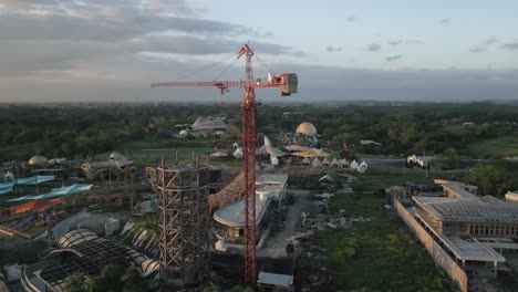 Beach-resort-on-Bali-under-construction,-aerial-orbits-tower-crane